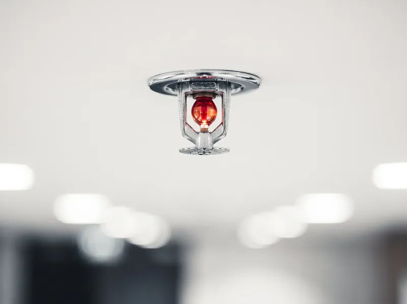 Close-up of a fire sprinkler head with a red glass bulb